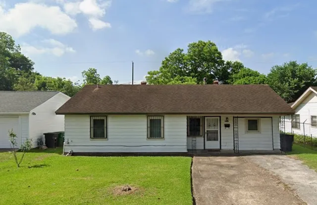 a front view of a house with a garden and trees