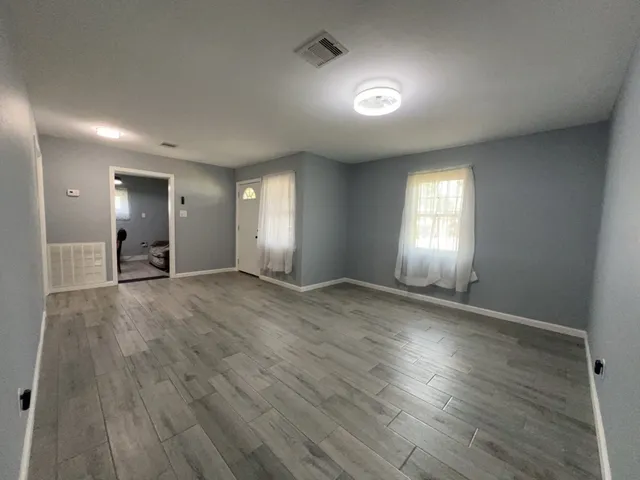 an empty room with wooden floor and windows