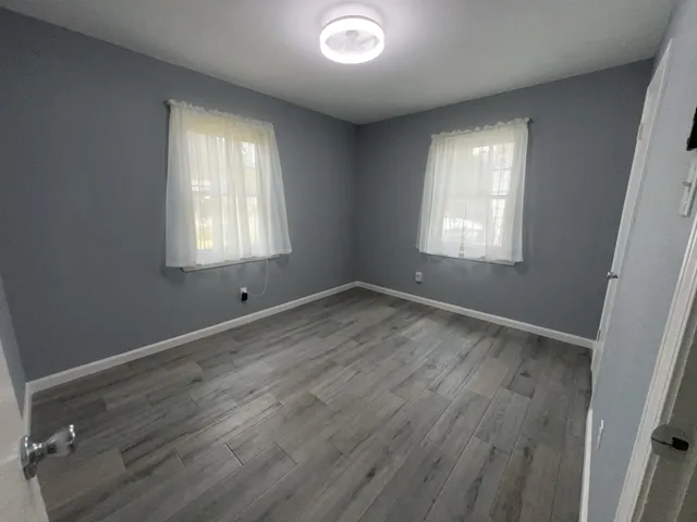 an empty room with wooden floor and windows