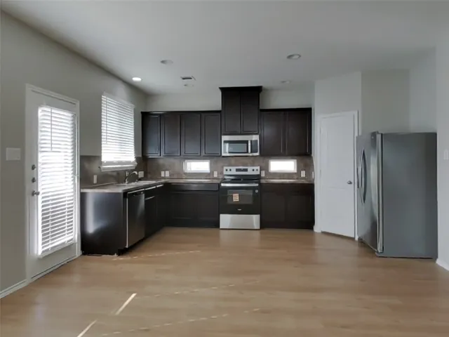 a kitchen with granite countertop a refrigerator and cabinets