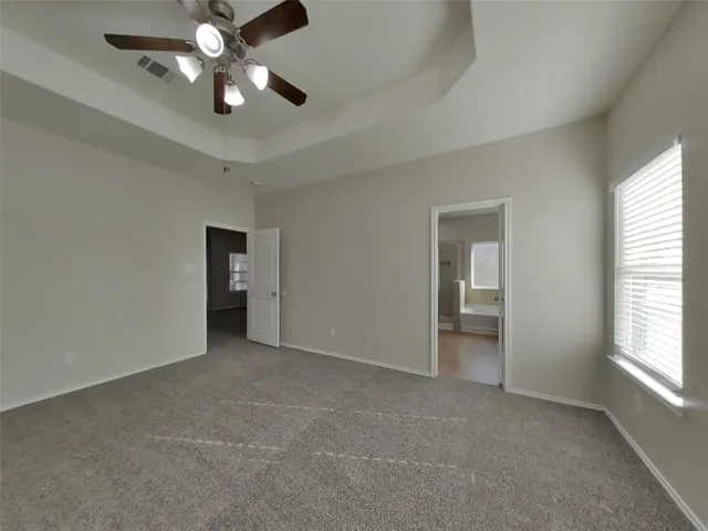 an empty room with chandelier fan and windows