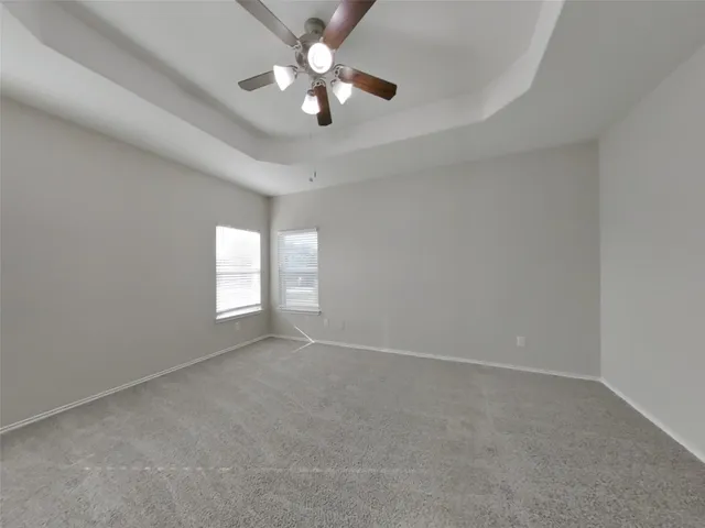 an empty room with a chandelier fan and windows