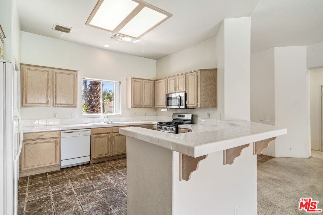68420 Riviera Road Cathedral City, CA 92234 - Photo 13 of 42 a kitchen with kitchen island granite countertop a sink appliances cabinets and furniture
