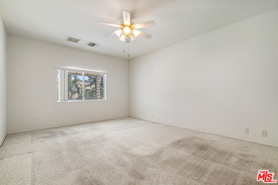 68420 Riviera Road Cathedral City, CA 92234 - Photo 18 of 42 an empty room with a chandelier fan and windows
