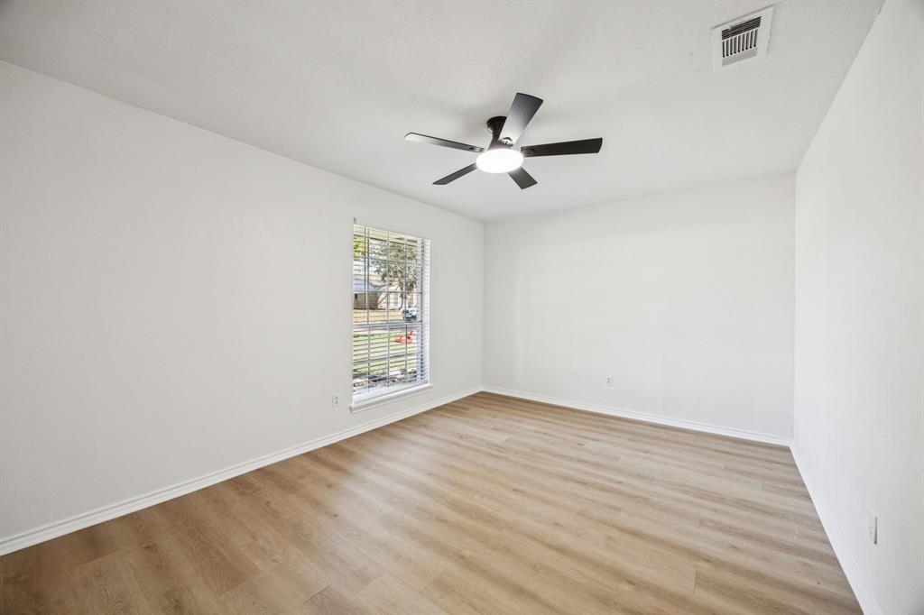 5909 Mark Lane Rowlett, TX 75089 - Photo 19 of 28 an empty room with wooden floor chandelier fan and windows