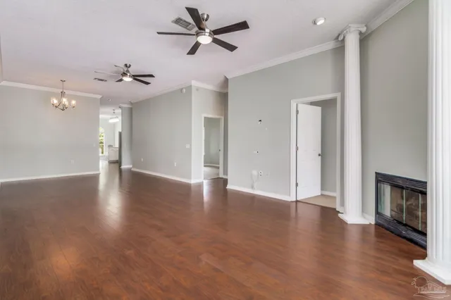 a view of an empty room with wooden floor and a ceiling fan