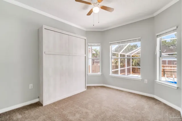 an empty room with chandelier fan and windows
