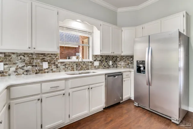 a kitchen with white cabinets white stainless steel appliances and sink