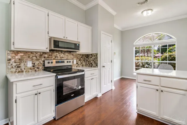 a kitchen with stainless steel appliances granite countertop a stove and white cabinets