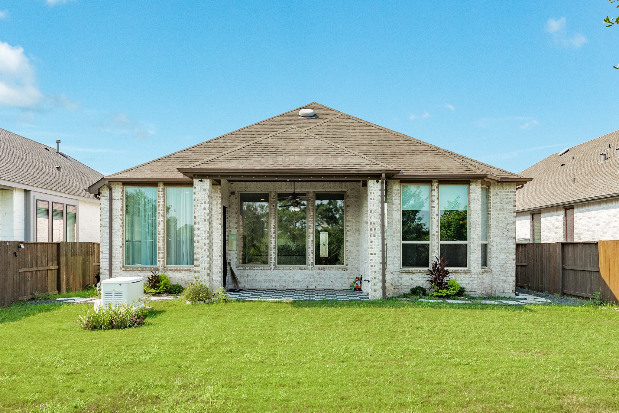4015 Shackleton Court Iowa Colony, TX 77583 - Photo 28 of 50 Stunning covered patio overlooking a spacious backyard, perfect for outdoor entertaining. The home features an impressive rear elevation with floor-to-ceiling windows that flood the living space with natural light. Peace of mind is guaranteed with the included full-home generator.