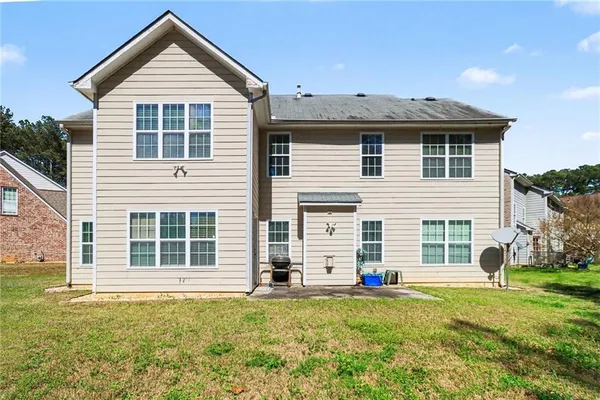 a view of a house with a yard and large tree