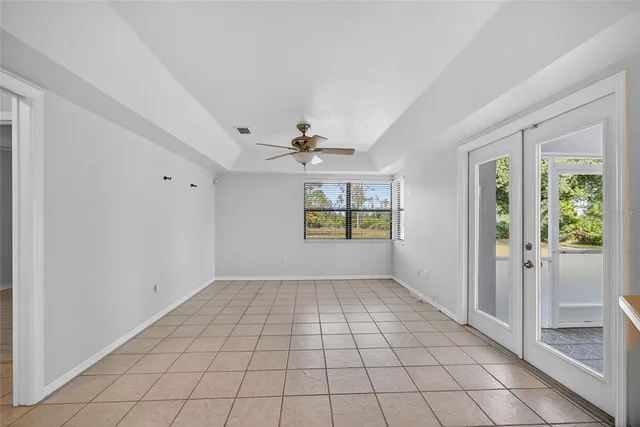a view of an empty room with window and chandelier fan