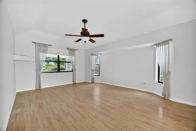 a view of an empty room with window and wooden floor