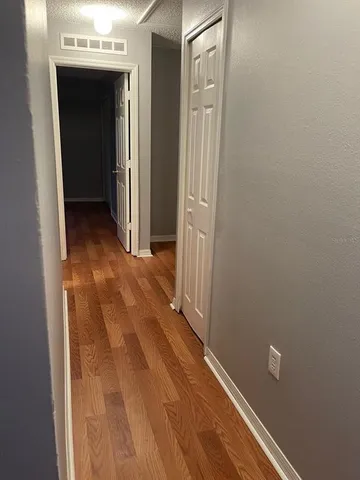 a view of a hallway with wooden floor and a bathroom
