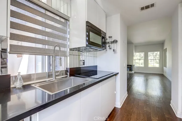 a kitchen with stainless steel appliances granite countertop a sink a stove and a wooden floor
