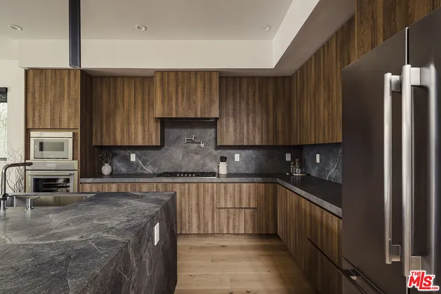 a kitchen with stainless steel appliances granite countertop a stove a sink and a refrigerator