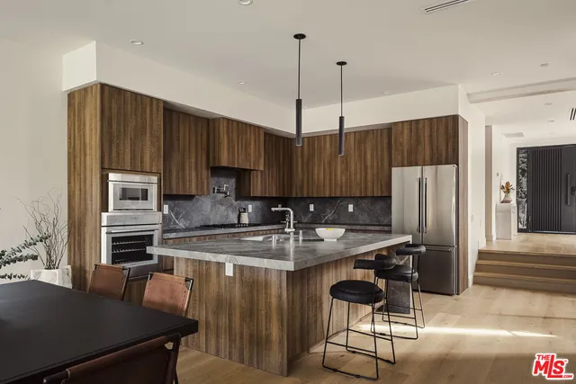 a kitchen with kitchen island granite countertop a stove a sink dishwasher and a refrigerator with wooden floor