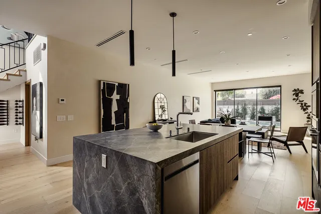 a kitchen with kitchen island granite countertop a sink a counter top space appliances and cabinets