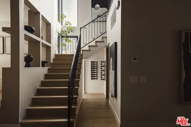 a view of staircase with lots of frames on wall and a window