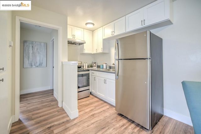 a kitchen with a refrigerator a stove top oven and cabinets