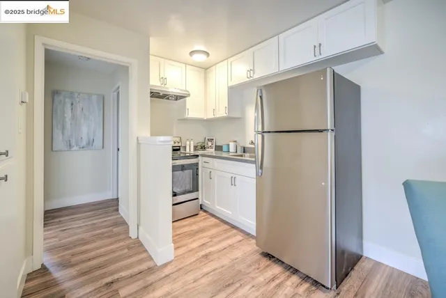 a kitchen with a refrigerator a stove top oven and cabinets