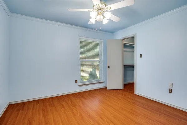 an empty room with wooden floor chandelier fan and windows