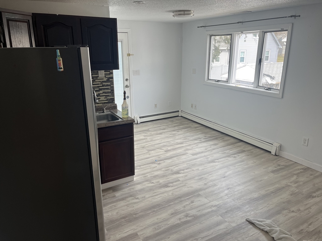 58 Brunswick Street Lowell, MA 01852 - Photo 11 of 33 a view of a kitchen with wooden floor and a refrigerator