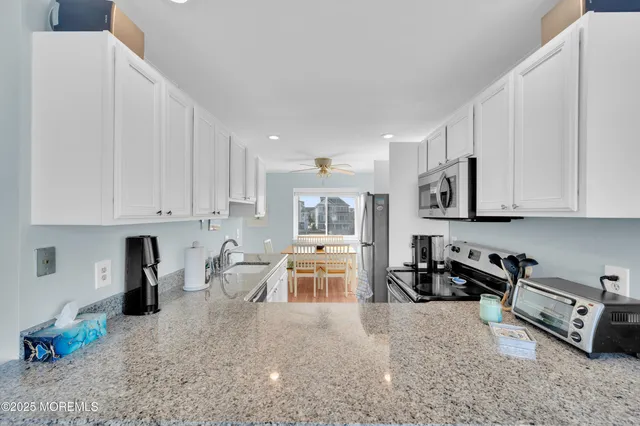 a kitchen with stainless steel appliances granite countertop a sink stove and white cabinets