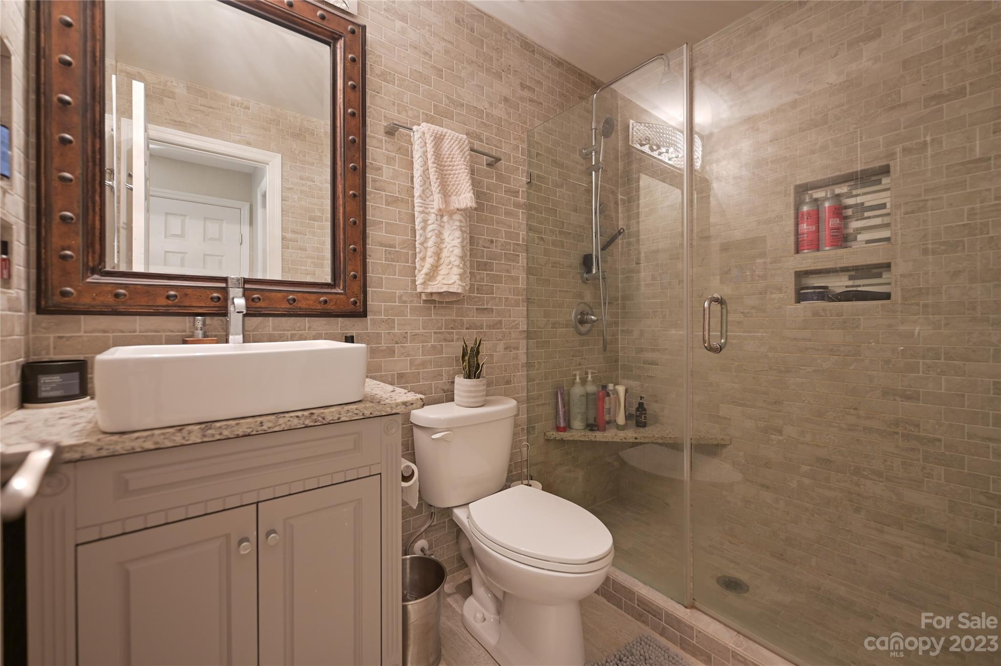 20109 Henderson Road, Unit D Cornelius, NC 28031 - Photo 18 of 18 a bathroom with a granite countertop toilet a sink and a mirror