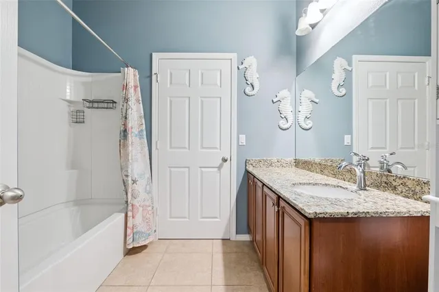 a bathroom with a granite countertop sink a mirror a bathtub and shower