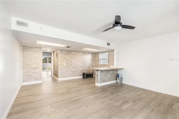 an empty room with wooden floor cabinet and windows