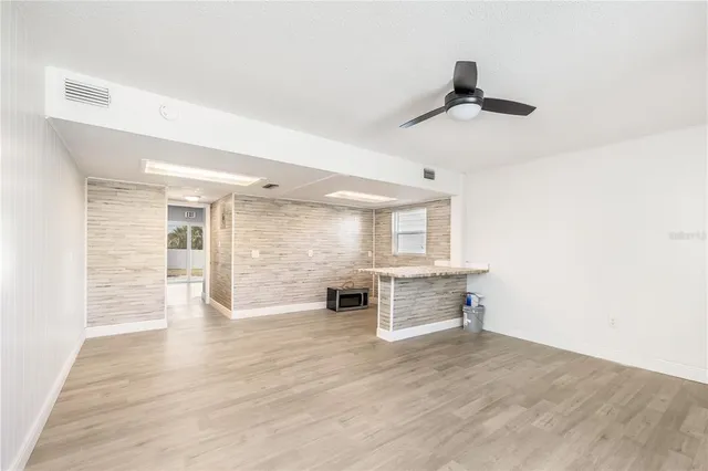 an empty room with wooden floor cabinet and windows