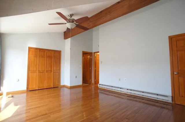 an empty room with wooden floor and a ceiling fan