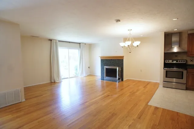 a view of empty room with wooden floor and kitchen