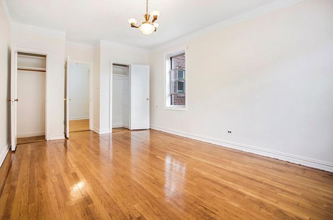 79-01 35th Avenue, Unit 4F Queens, NY 11372 - Photo 8 of 11 an empty room with wooden floor and windows