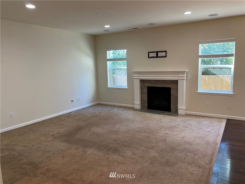 3406 176th Place Southeast Bothell, WA 98012 - Photo 3 of 19 an empty room with windows fireplace and wooden floor