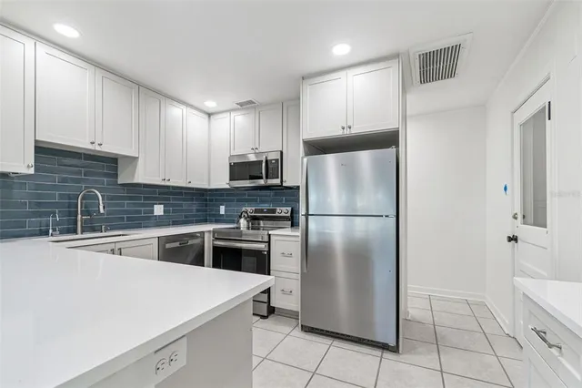 a kitchen with white cabinets and appliances