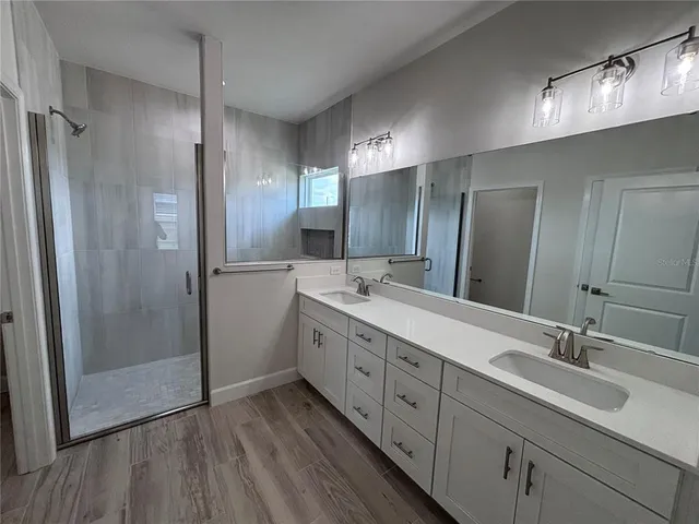 a bathroom with double vanity sink and shower