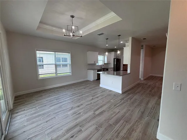 an open kitchen with chandelier and wooden floor