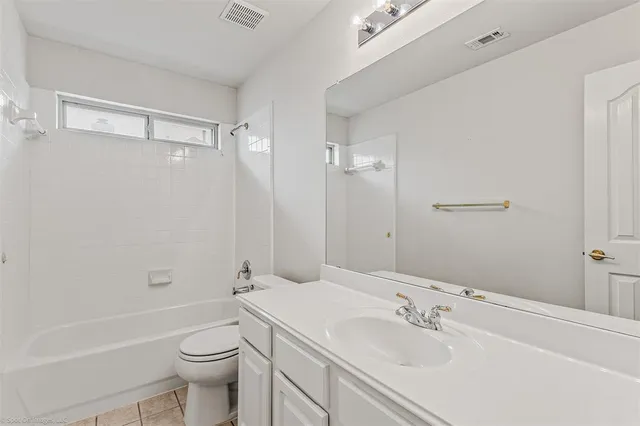 an empty room with chandelier fan and windows