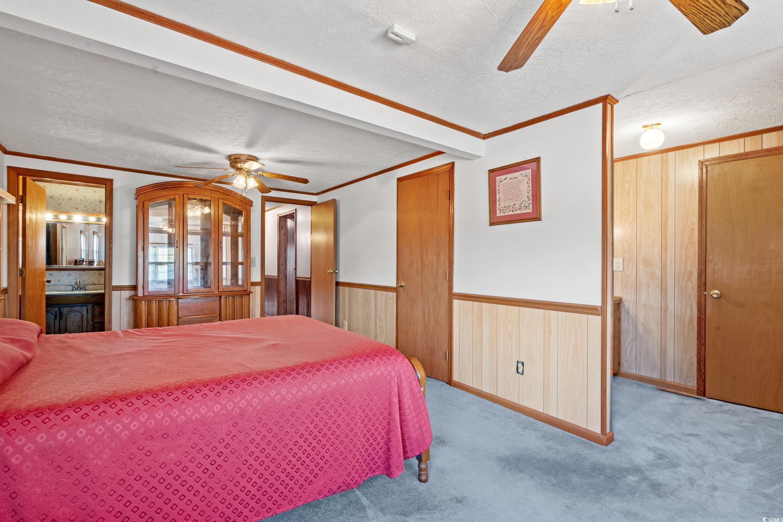 4422 Grady Road Mullins, SC 29574 - Photo 9 of 28 Bedroom featuring a textured ceiling, ceiling fan, crown molding, carpet floors, and wooden walls