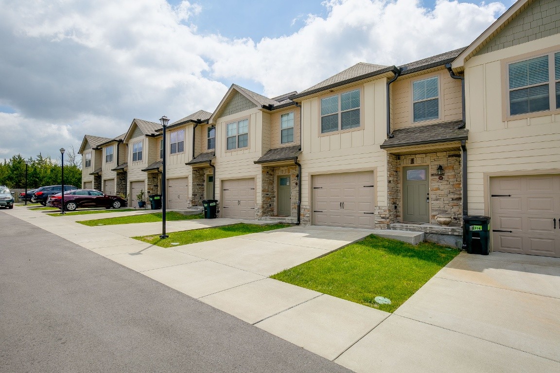 272 Signature Place Lebanon, TN 37087 - Photo 3 of 36 a view of a white house with a yard and table and chairs under an umbrella