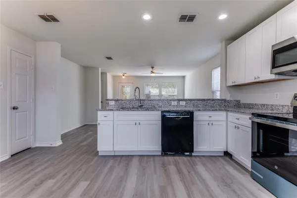 a kitchen with stainless steel appliances granite countertop a stove a sink and a microwave