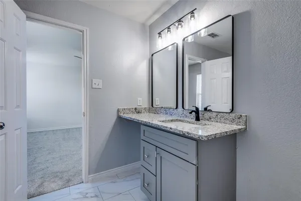 a bathroom with a granite countertop sink and a mirror