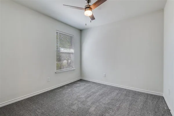 an empty room with a window and a ceiling fan