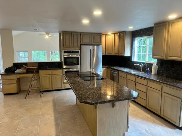 a kitchen with stainless steel appliances granite countertop a sink a stove and refrigerator
