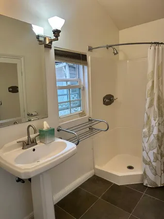 a bathroom with a sink shower and a mirror