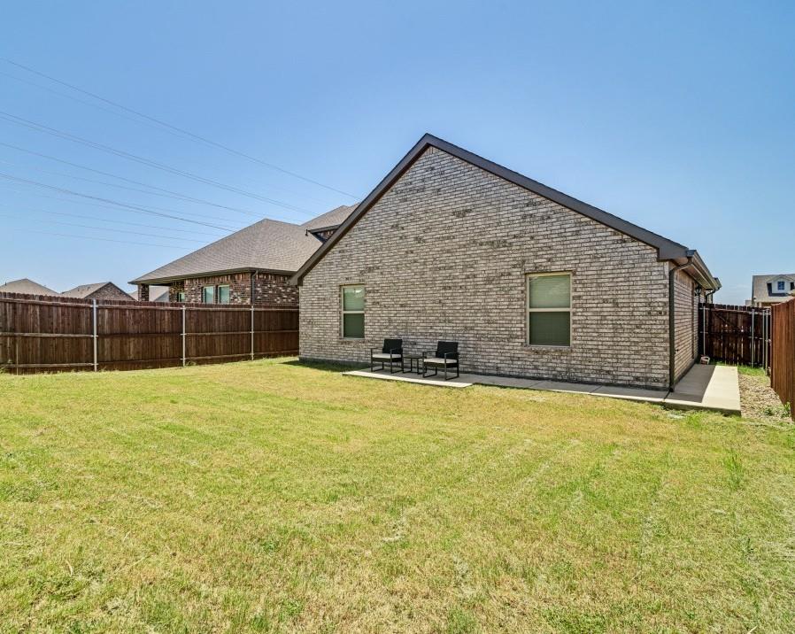 609 Nature Stroll Road Lavon, TX 75166 - Photo 12 of 13 Expansive backyard featuring a manicured lawn, full privacy fencing, a concrete patio, and a brick exterior with dark trim