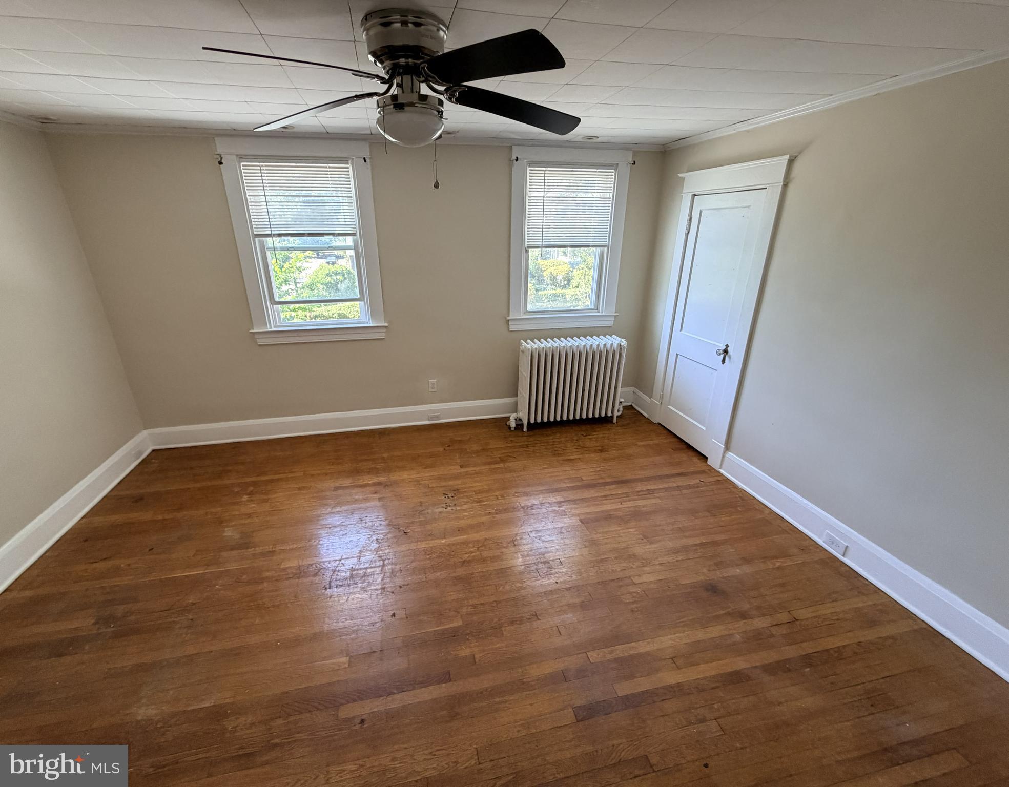 506 Cedarcroft Road Baltimore, MD 21212 - Photo 8 of 16 an empty room with wooden floor fan and windows