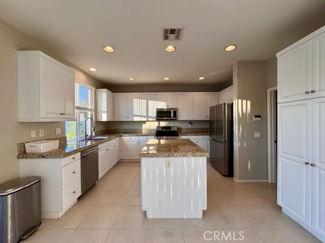 a kitchen with stainless steel appliances granite countertop a sink stove refrigerator and cabinets
